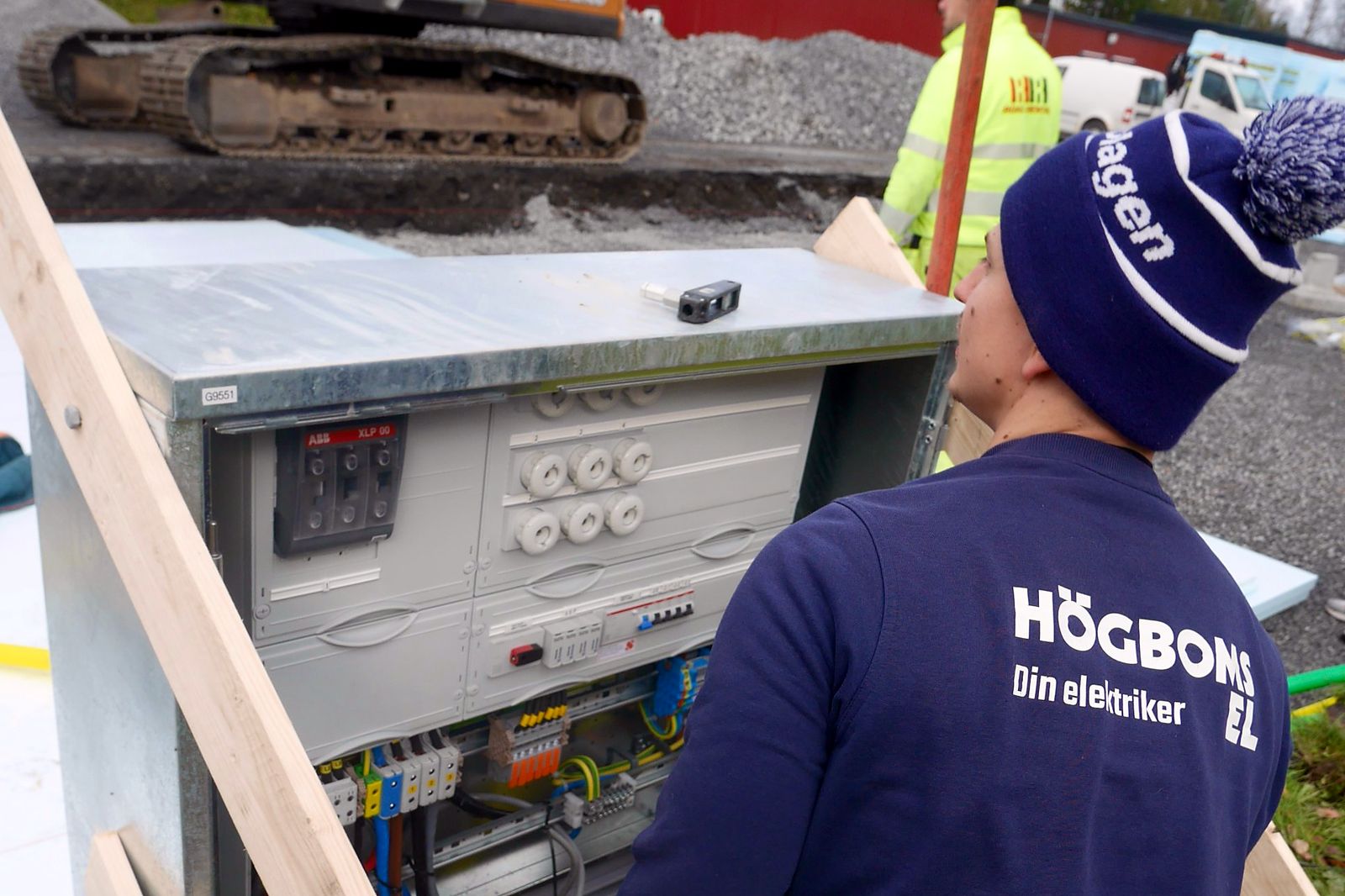 Elektriker från Högboms El kopplar i ett kopplingsskåp på en byggarbetsplats