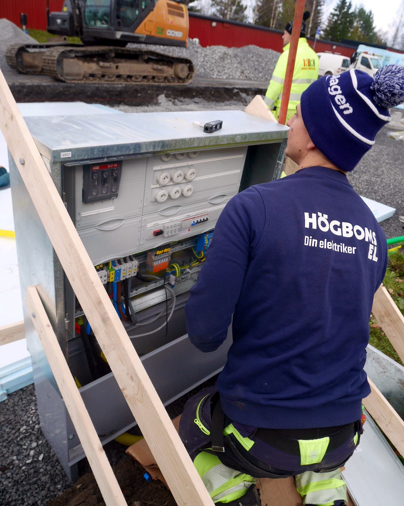 Elektriker från Högboms El i arbetskläder vid ett kopplingsskåp