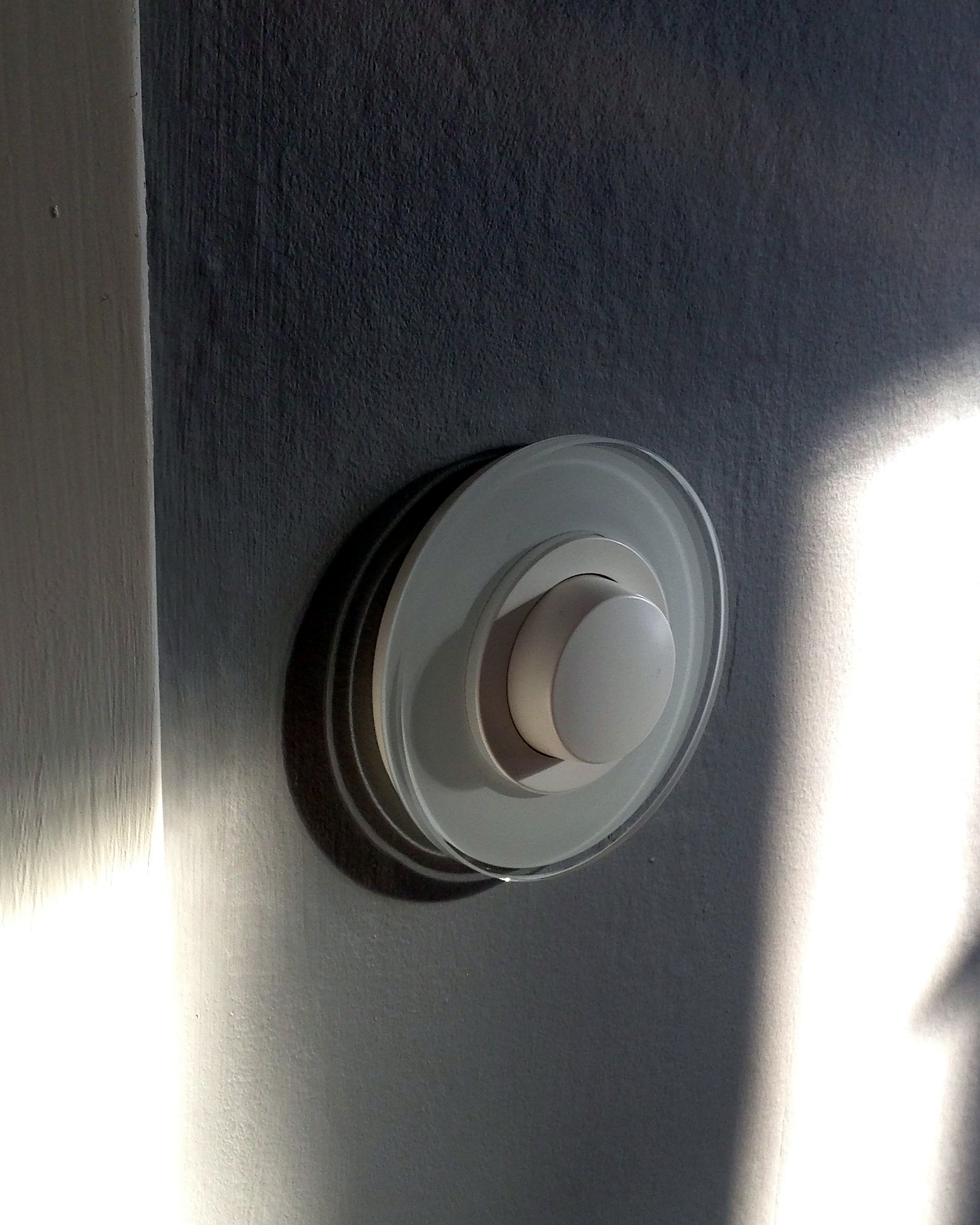 Rund vit tryckknapp med glasram i solljus