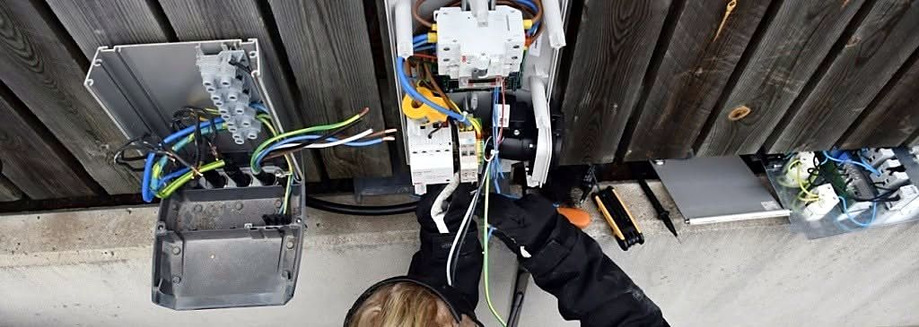 Elektriker kopplar in en laddbox på en husvägg